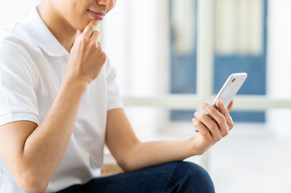 スマホを見つめて笑顔の男性