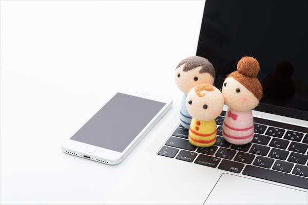 家族の人形が乗ったノートパソコンとスマートフォン