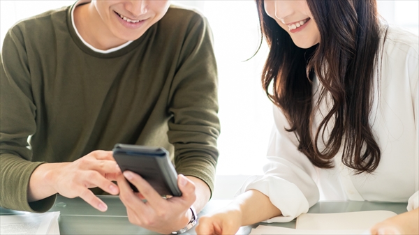 スマホの画面を見ながら笑顔で話す男女
