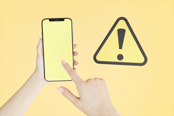 黄色い注意マークと黄色い画面が表示されたスマートフォン
