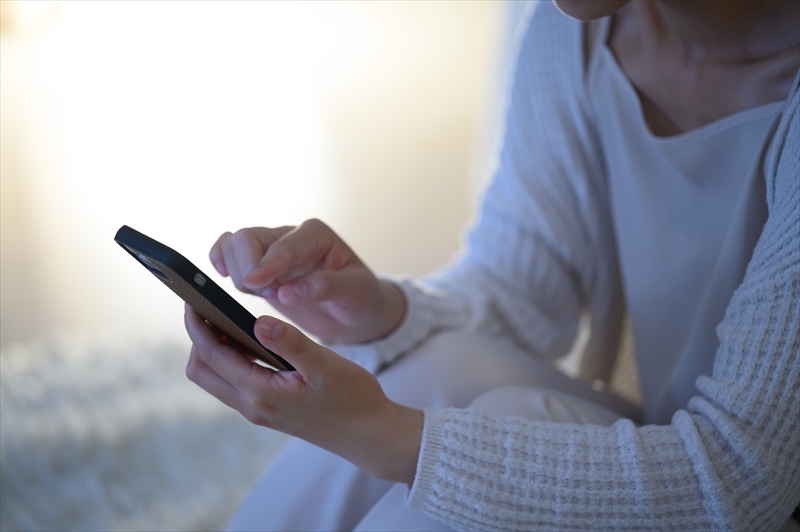 暗い部屋でスマホを操作する女性