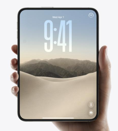 iPhone Duoを閉じた状態で片手に持った製品写真。5.4インチのアウターディスプレイにロック画面の時計と壁紙が表示されている