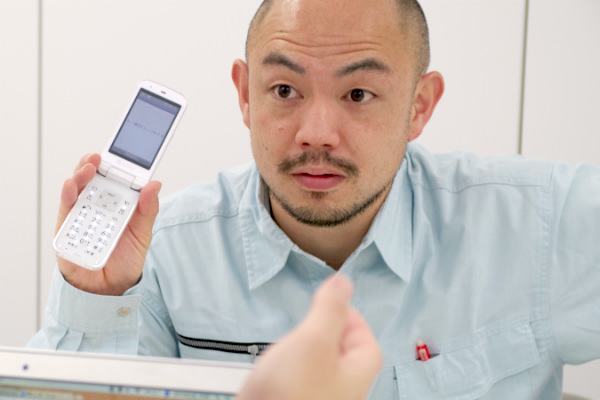 ガラケーを見せる小さいおじさん