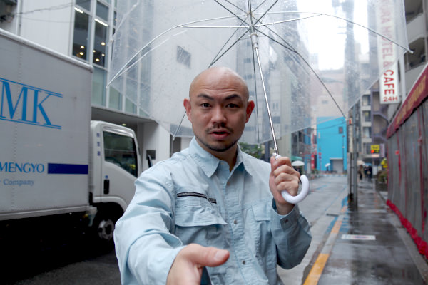 傘を片手に握手を求める小さいおじさん