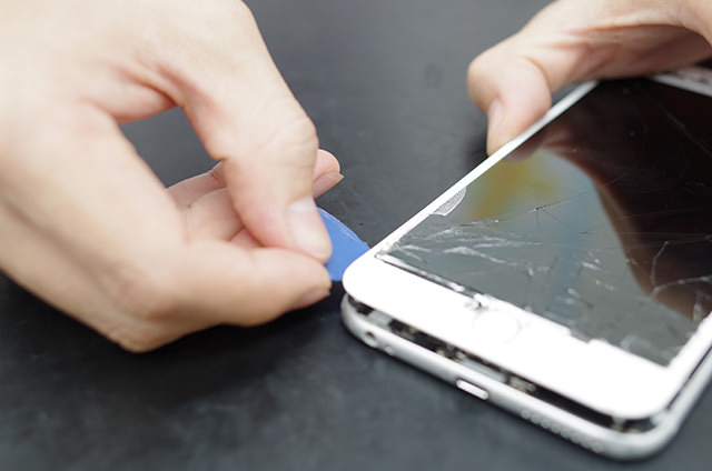 ネジを外したらギターのピックらしきものでiPhoneを開け始めた